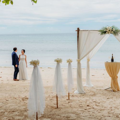 A couple standing on the beach on their wedding day with a beautiful decor for their wedding at the beach